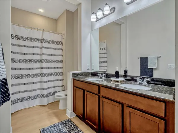 a bathroom with a granite countertop sink a toilet and a mirror