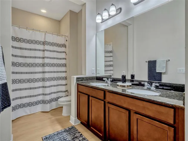 a bathroom with a granite countertop sink a toilet and a mirror