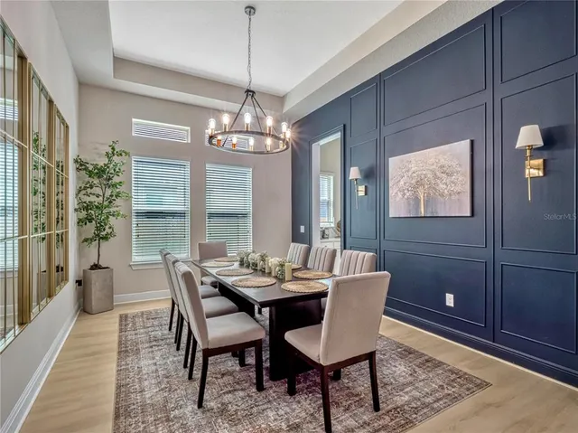 a dining room with wooden floor a chandelier a wooden table and chairs