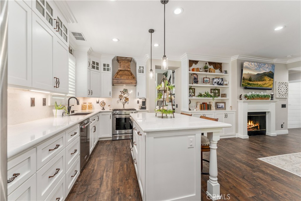 8750 East Heatherwood Road Anaheim Hills, CA 92808 - Photo 12 of 60 a kitchen with stainless steel appliances granite countertop a stove top oven a sink dishwasher and a fireplace with wooden floor