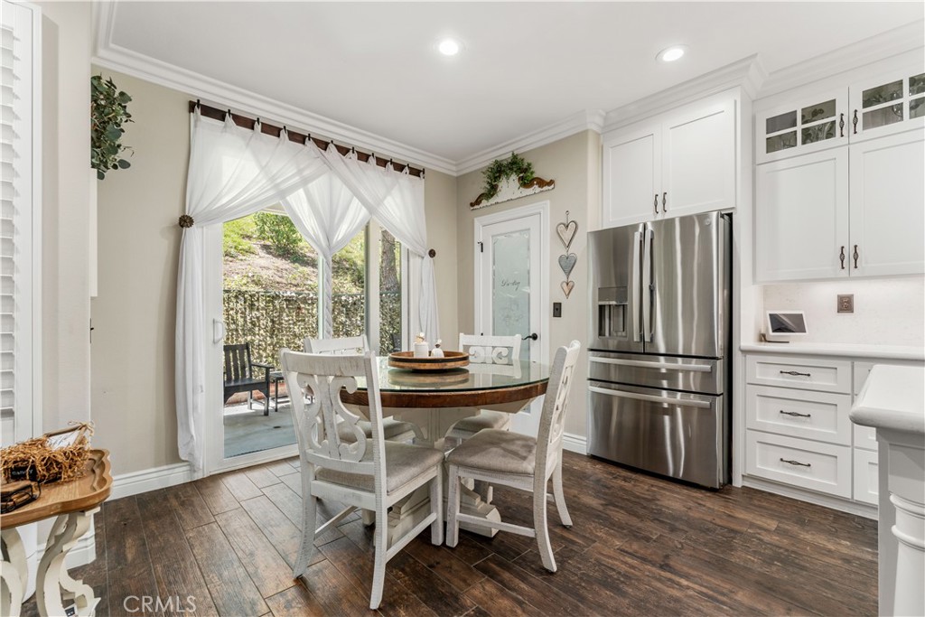 8750 East Heatherwood Road Anaheim Hills, CA 92808 - Photo 14 of 60 a kitchen with stainless steel appliances a stove a refrigerator and a dining table with wooden floor