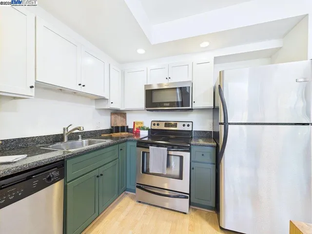 a kitchen with stainless steel appliances granite countertop a stove a sink and a refrigerator