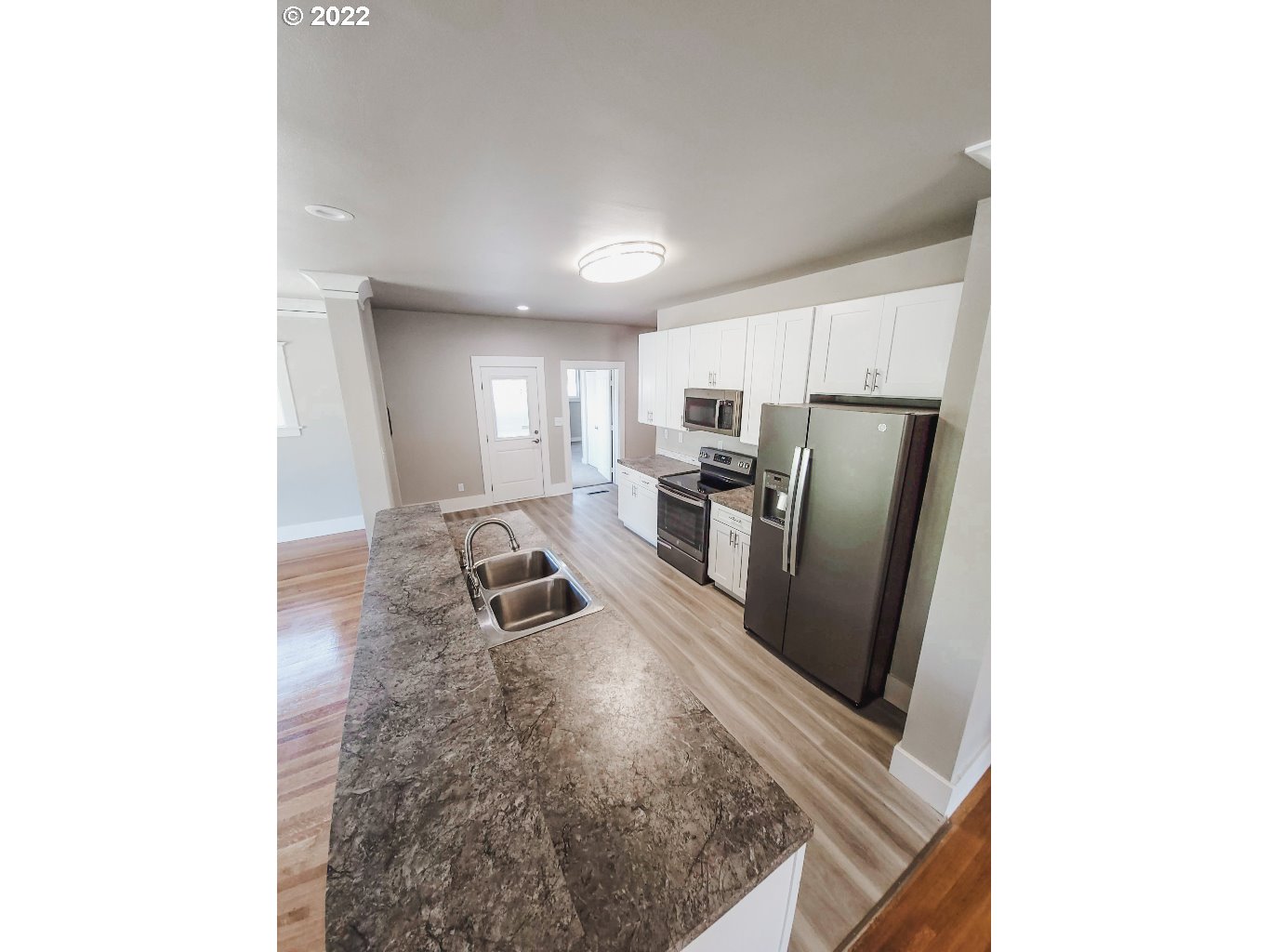 324 Northwest 9th Street Pendleton, OR 97801 - Photo 7 of 24 a kitchen with stainless steel appliances granite countertop a refrigerator a stove and a sink with wooden floor