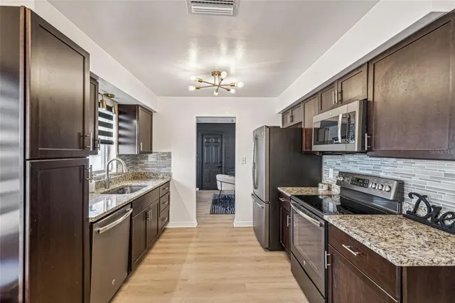 a kitchen with stainless steel appliances granite countertop a refrigerator a stove and a sink