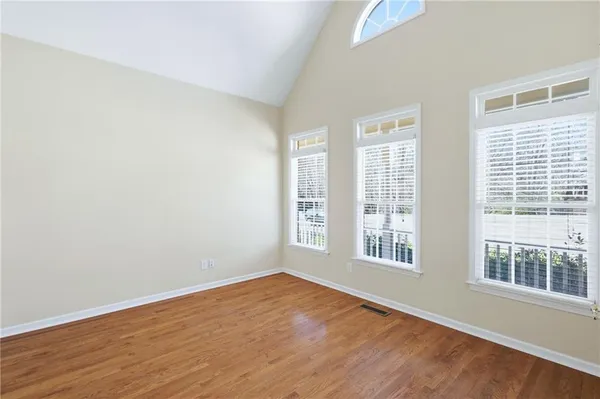 a view of an empty room with wooden floor and windows
