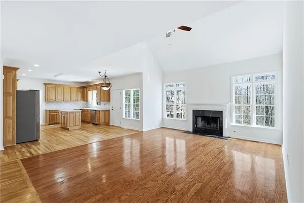 a view of an empty room with wooden floor and a fireplace