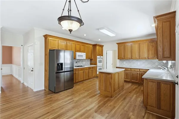 a kitchen with stainless steel appliances granite countertop a refrigerator a sink dishwasher a stove with wooden cabinets and floor