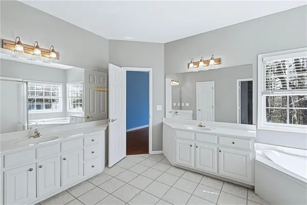 a spacious bathroom with a double vanity sink a large mirror and a bathtub