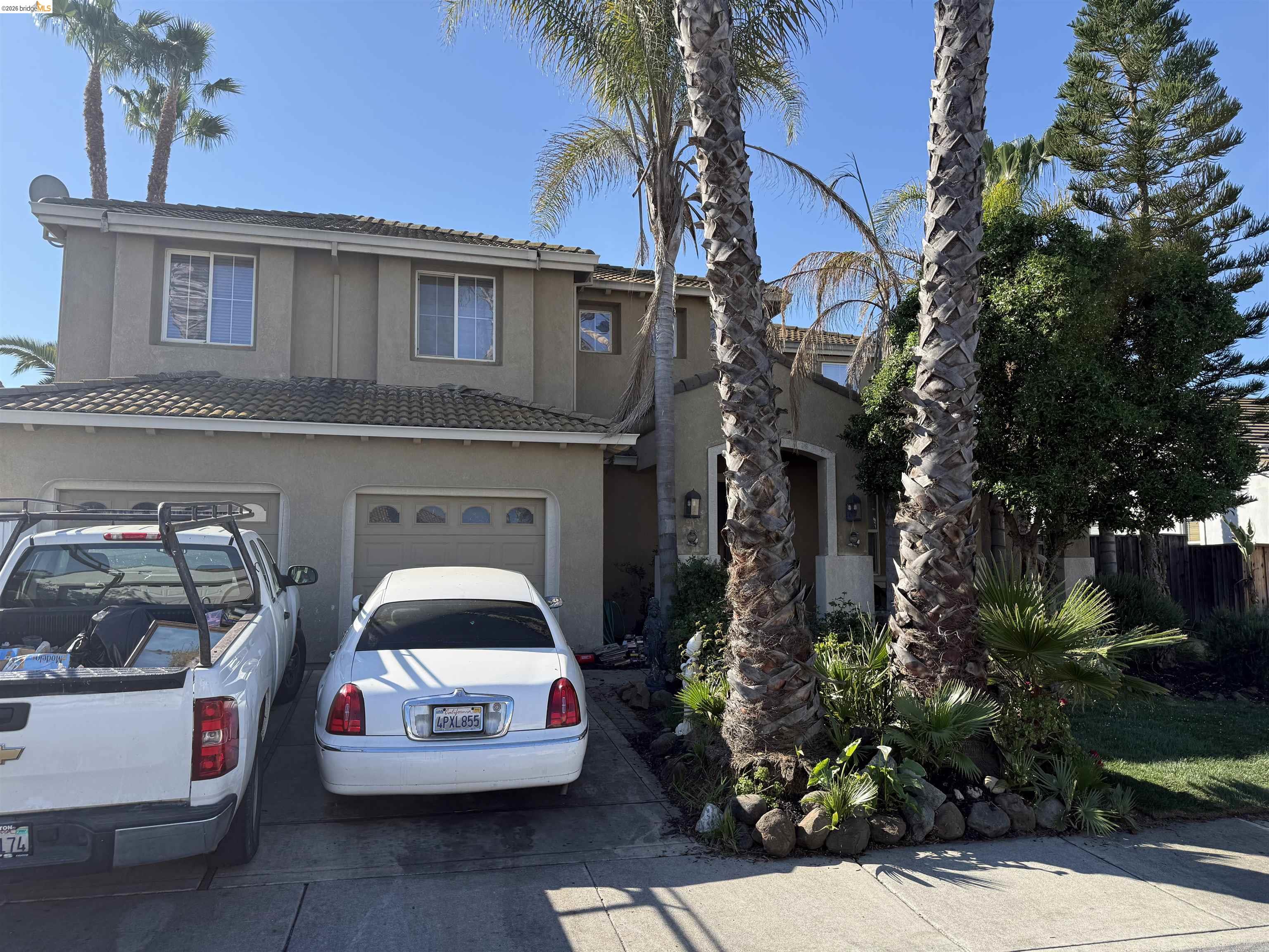 View of front facade with driveway, a garage, and stucco siding