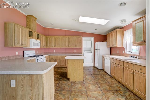 1435 Equestrian Point Yoder, CO 80864 - Photo 14 of 49 Kitchen with white appliances, washer / dryer, ornamental molding, a skylight, and light brown cabinetry
