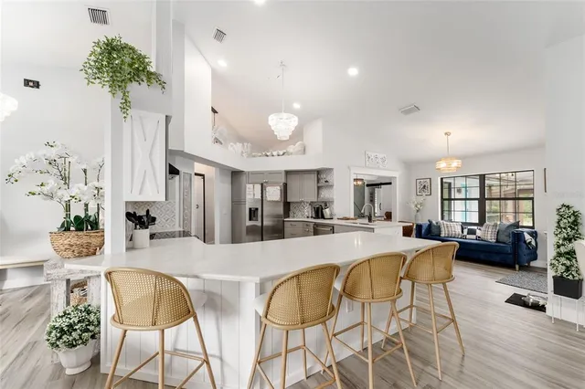 a dining room with wooden floor a chandelier a wooden table and chairs