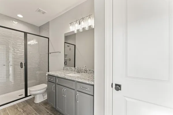 a bathroom with a granite countertop sink toilet a large mirror a vanity and shower