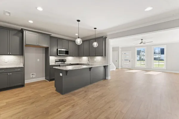 a large kitchen with stainless steel appliances kitchen island granite countertop a large counter top and wooden floors