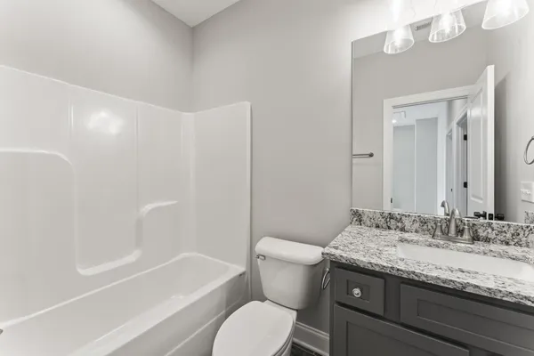 a bathroom with a granite countertop sink a toilet and bathtub