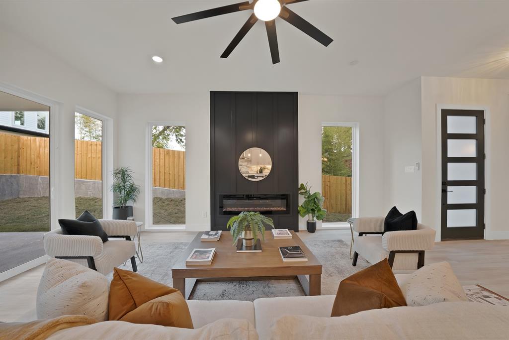 1415 Fayette Street Dallas, TX 75203 - Photo 9 of 40 Spacious living area featuring a modern fireplace with a black shiplap surround, light wood-finish flooring, and multiple large windows