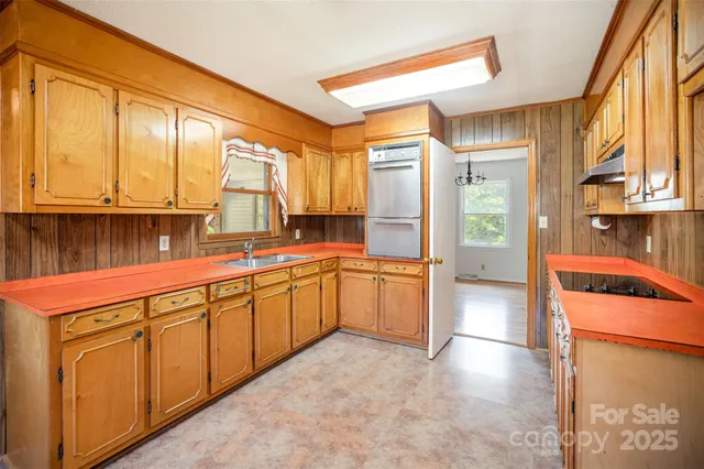 a large kitchen with stainless steel appliances granite countertop a refrigerator a stove and a sink with wooden cabinets