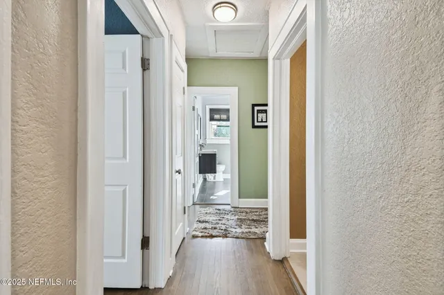 a view of a hallway with wooden floor near a corridor