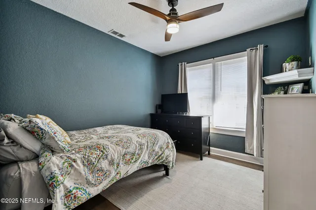 a bedroom with a bed and a flat tv screen on dresser