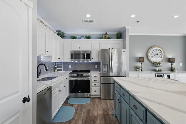 a kitchen with stainless steel appliances granite countertop a sink stove refrigerator and cabinets