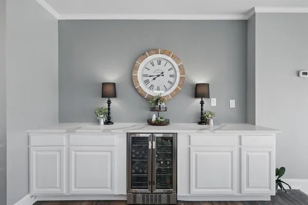 a large kitchen with cabinets chairs and wooden floor