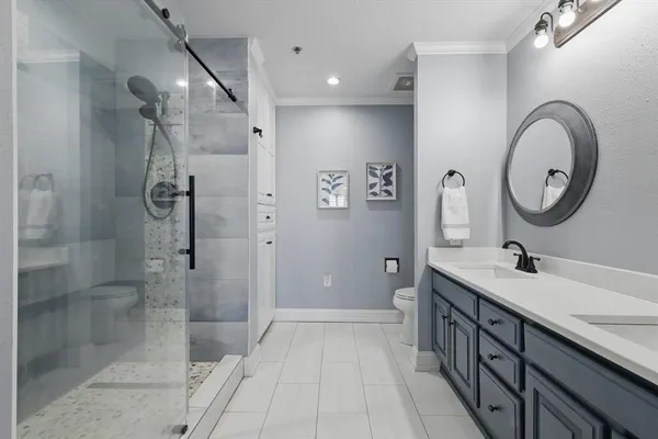 a bathroom with a double vanity sink a toilet a mirror and shower