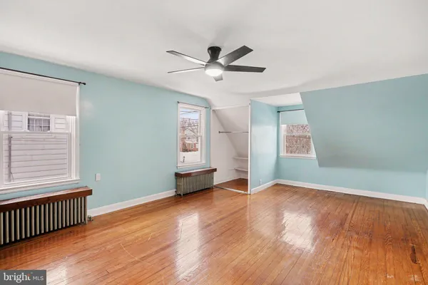 an empty room with wooden floor ceiling fan and windows
