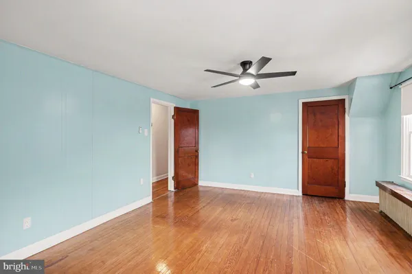 an empty room with wooden floor and ceiling fan