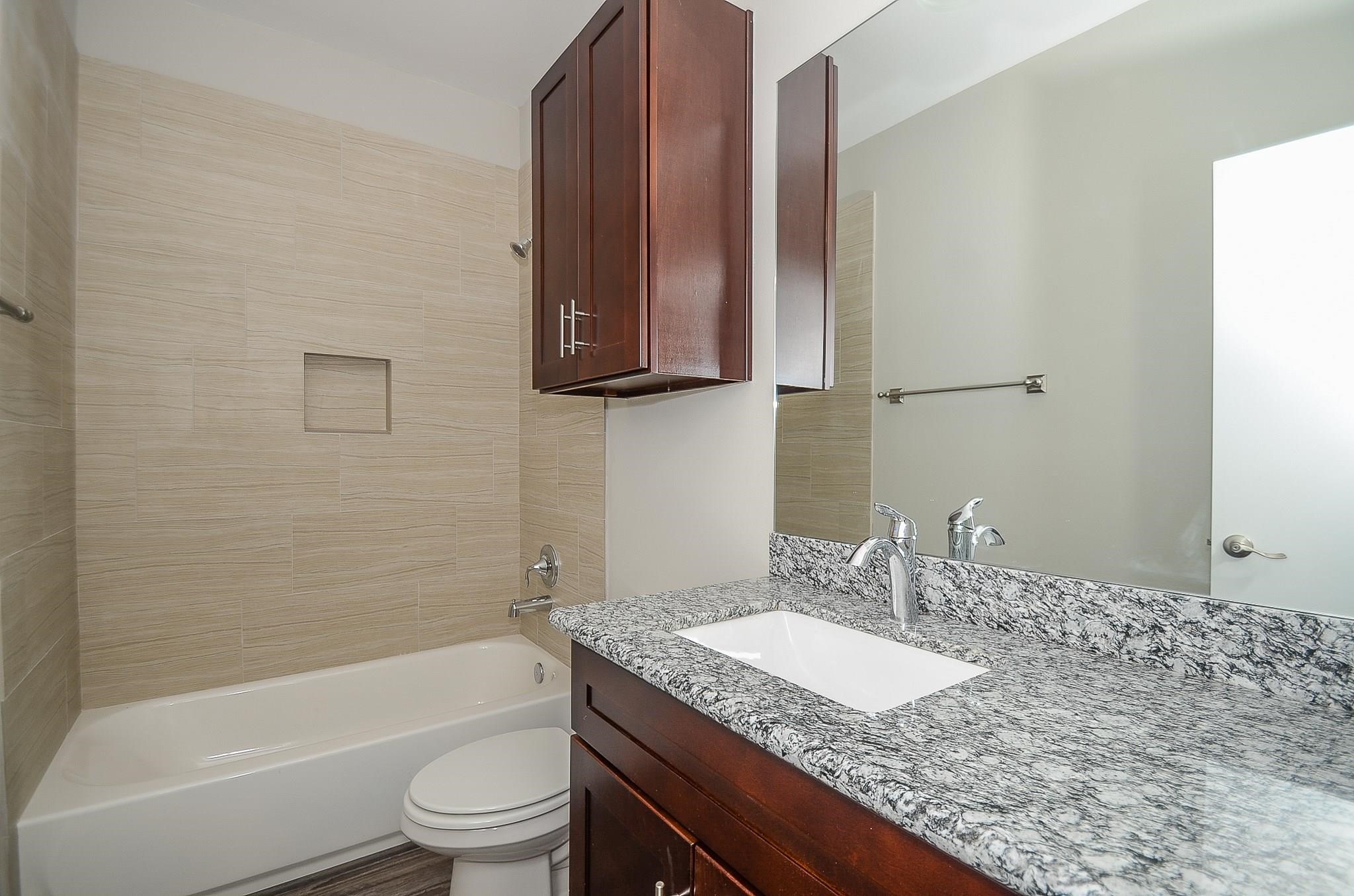 3249 Dixie Drive, Unit B Houston, TX 77021 - Photo 18 of 25 a bathroom with a granite countertop sink a toilet and bathtub