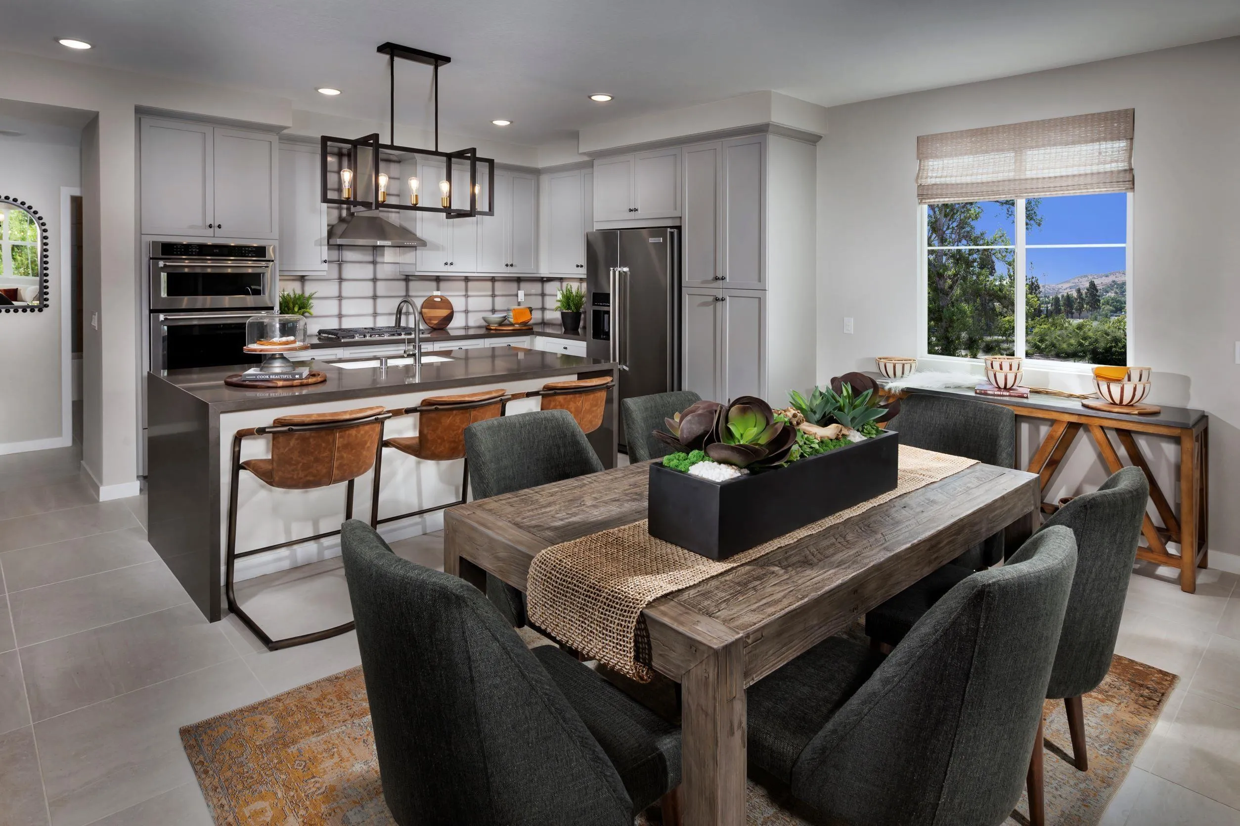 a kitchen with stainless steel appliances granite countertop a stove a refrigerator a sink a dining table and chairs