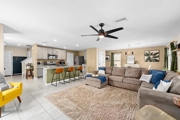 a living room with furniture kitchen view and a chandelier