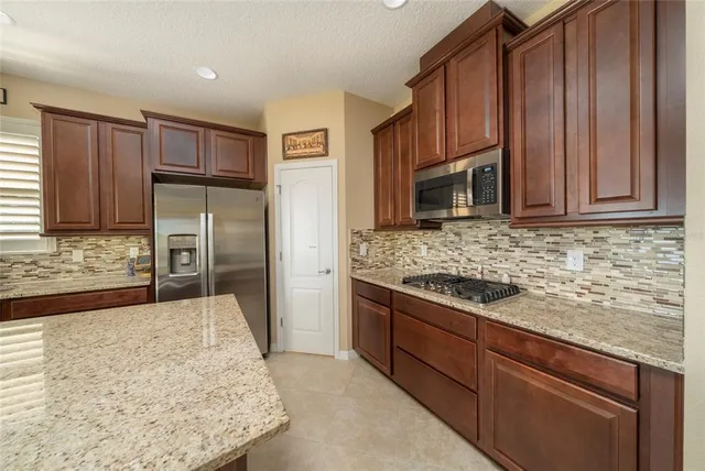 a kitchen with stainless steel appliances granite countertop wooden cabinets a granite counter and a refrigerator