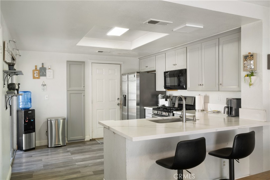 11840 Rustic Place Fontana, CA 92337 - Photo 5 of 20 a kitchen with stainless steel appliances a sink a microwave a refrigerator and chairs