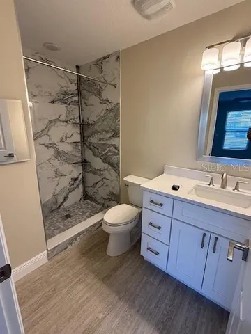 a bathroom with a granite countertop sink toilet a shower and a mirror