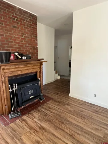 a view of an empty room with wooden floor and a fireplace