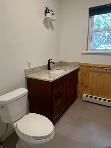 a bathroom with a granite countertop toilet sink and mirror