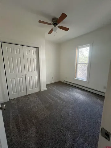an empty room with a ceiling fan and window