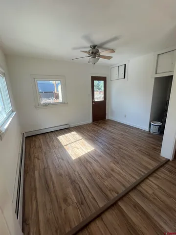 a view of empty room with wooden floor and fan