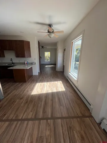 a view of kitchen and empty room with wooden floor