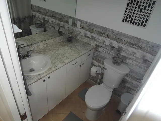 a bathroom with a granite countertop toilet and a sink