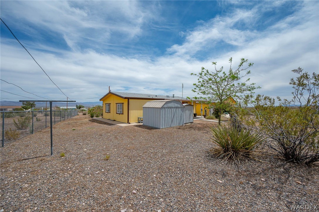 2465 Egar Road Golden Valley, AZ 86413 - Photo 60 of 98 The property features a spacious yard with a gravel surface, a visible yellow building, and a metal storage shed
