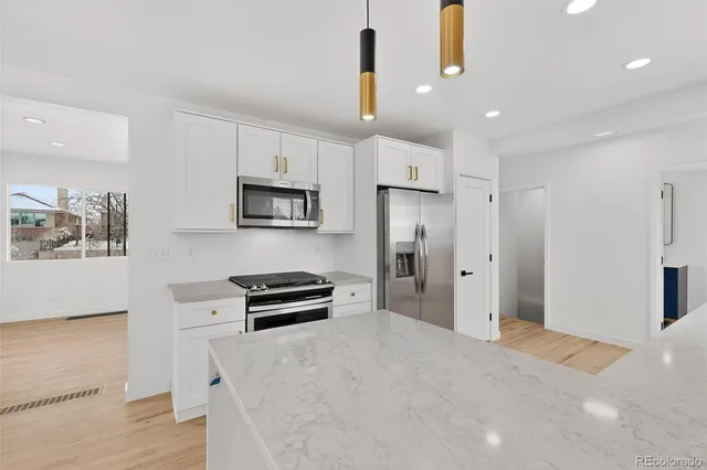 a kitchen with a sink dishwasher a refrigerator and white cabinets with wooden floor