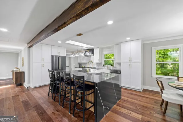 a kitchen with stainless steel appliances a dining table chairs stove refrigerator and cabinets