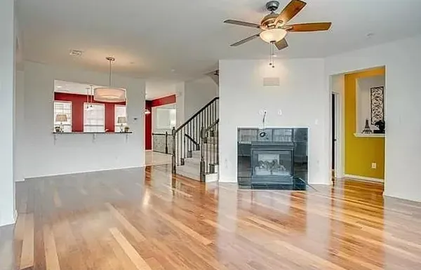 a view of a livingroom with wooden floor a ceiling fan and staircase
