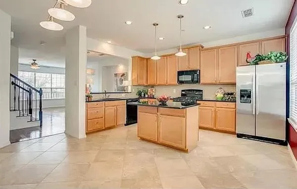 a kitchen with granite countertop a refrigerator oven a sink and cabinets