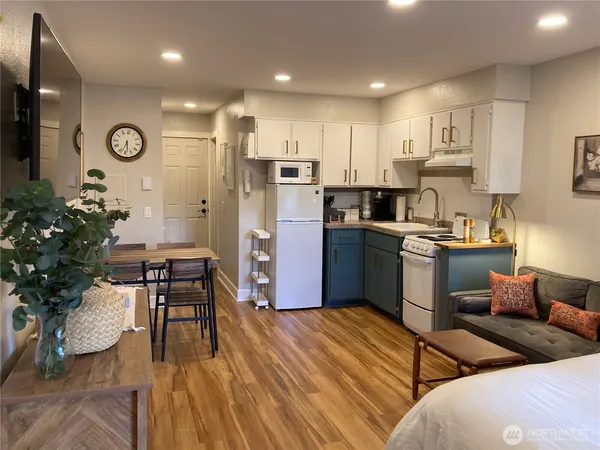 a kitchen with granite countertop a refrigerator oven a sink a dining table and chairs with wooden floor