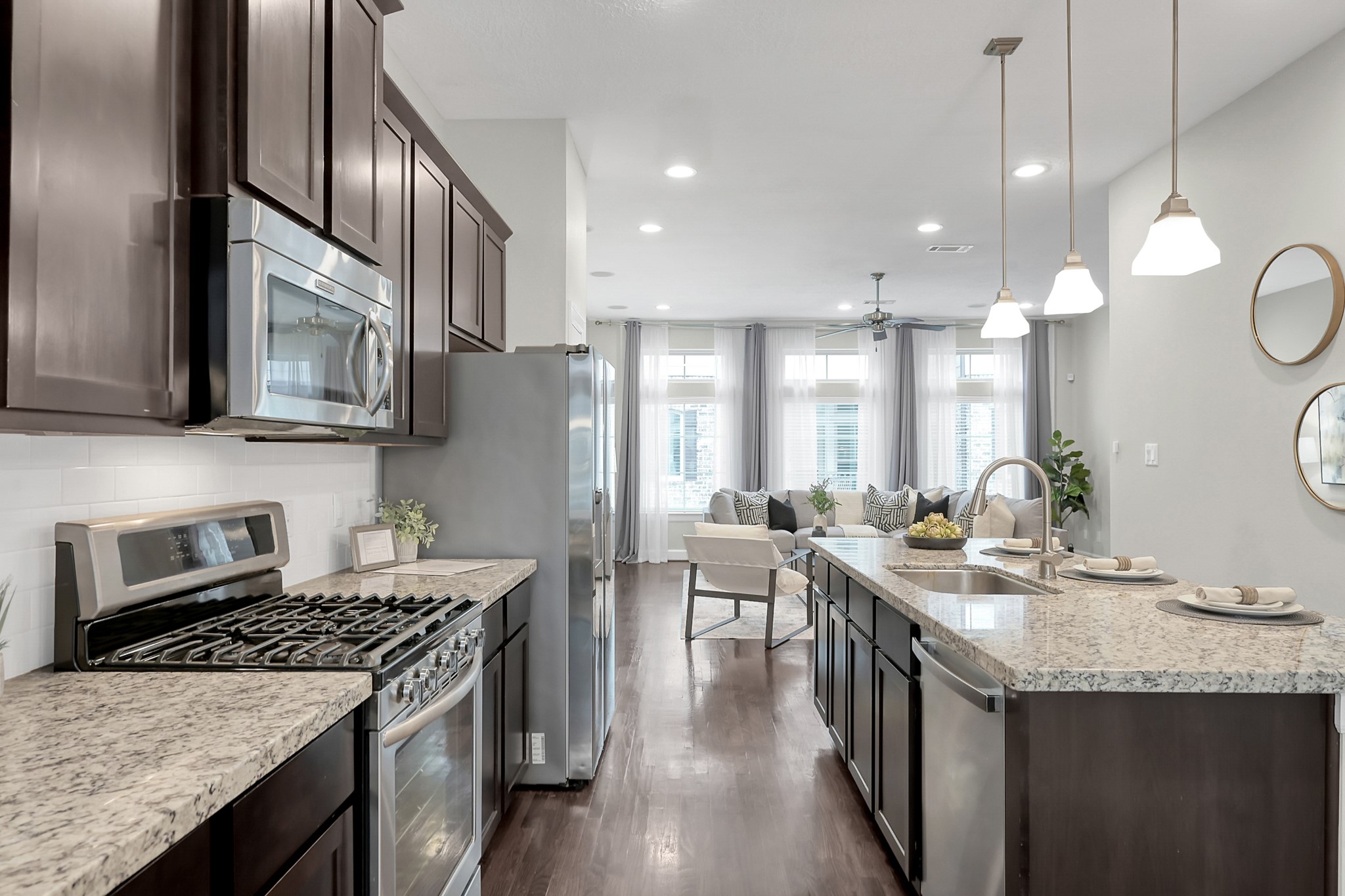 351 West 26th Street Houston, TX 77008 - Photo 14 of 45 This beautiful kitchen features sleek dark cabinetry, granite countertops, and stainless steel appliances. It opens into a bright living area with large windows, offering a seamless and inviting space.