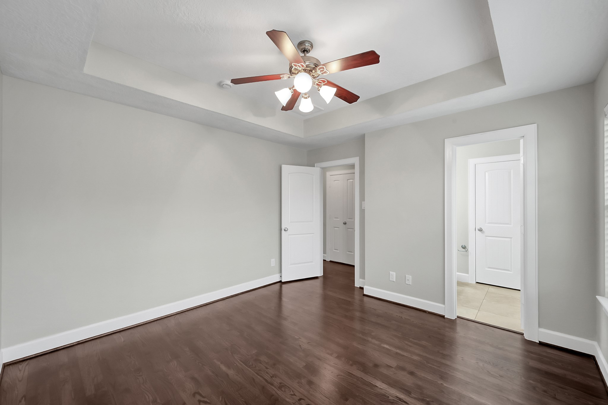 351 West 26th Street Houston, TX 77008 - Photo 31 of 45 This room features hardwood floors, neutral walls, and a ceiling fan with lights. It has a tray ceiling design, and doors leading to adjacent spaces, providing versatility and functionality.