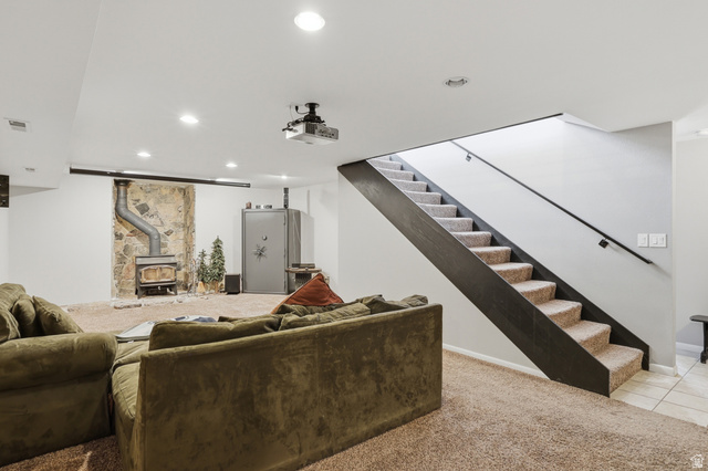 114 North Clark Lane Elk Ridge, UT 84651 - Photo 15 of 26 Finished lower level featuring a carpeted recreation area, stone accent wall with a wood-burning stove, and recessed lighting