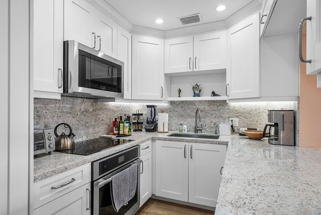 a kitchen with stainless steel appliances granite countertop a sink a stove a microwave and cabinets