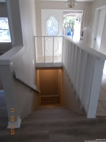 a view of a kitchen and an empty room with wooden floor and a kitchen